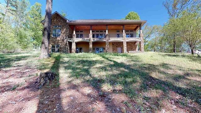 back of house with a lawn and a balcony