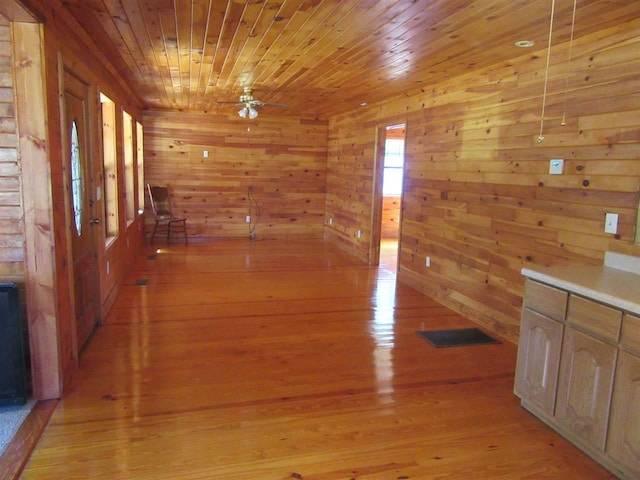 corridor with wooden ceiling, wooden walls, and light hardwood / wood-style flooring