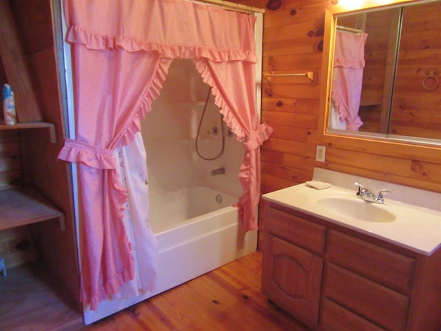 bathroom with wood walls, oversized vanity, wood-type flooring, and shower / bathtub combination with curtain