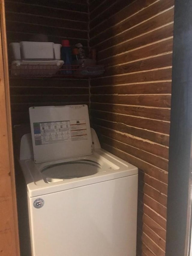 clothes washing area with wooden walls and washer / dryer