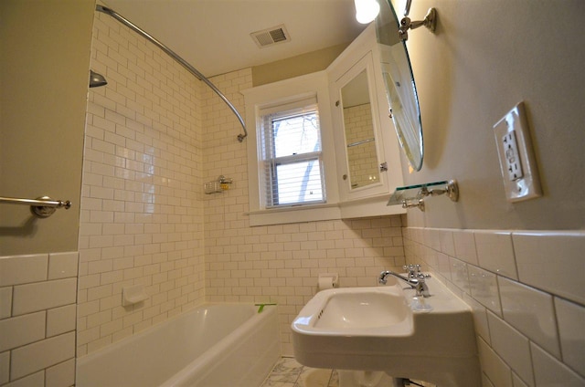 bathroom with tile walls and tiled shower / bath combo