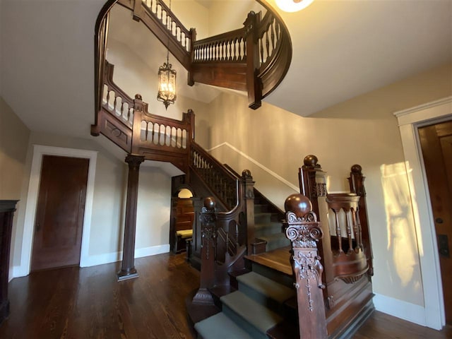 staircase featuring dark hardwood / wood-style floors and ornate columns