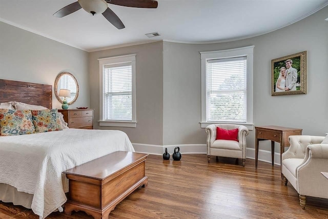 bedroom with ceiling fan, crown molding, dark wood-type flooring, and multiple windows