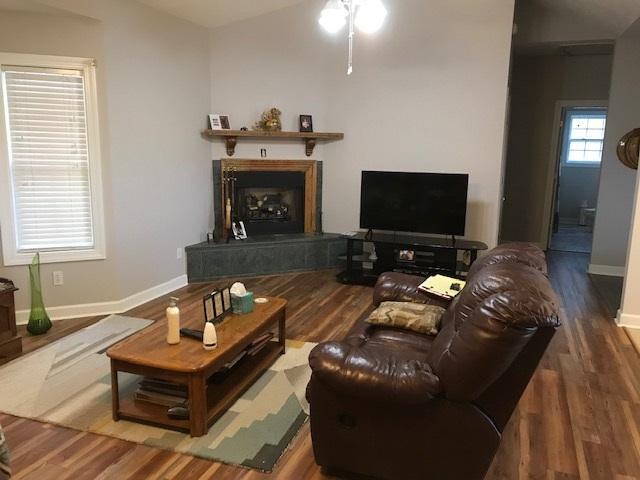 living room featuring ceiling fan, lofted ceiling, and dark wood-type flooring