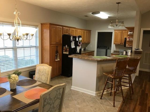 kitchen with a chandelier, pendant lighting, black refrigerator, a breakfast bar area, and washing machine and dryer