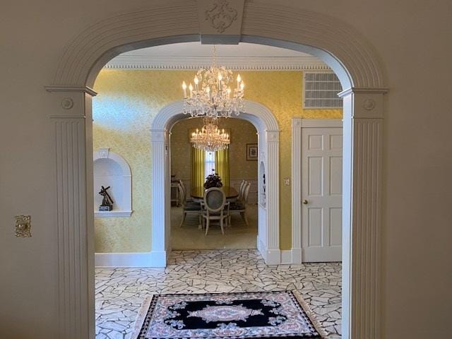 corridor with a notable chandelier and ornate columns