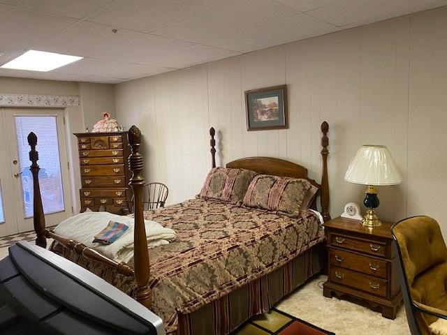 bedroom with light carpet and a paneled ceiling