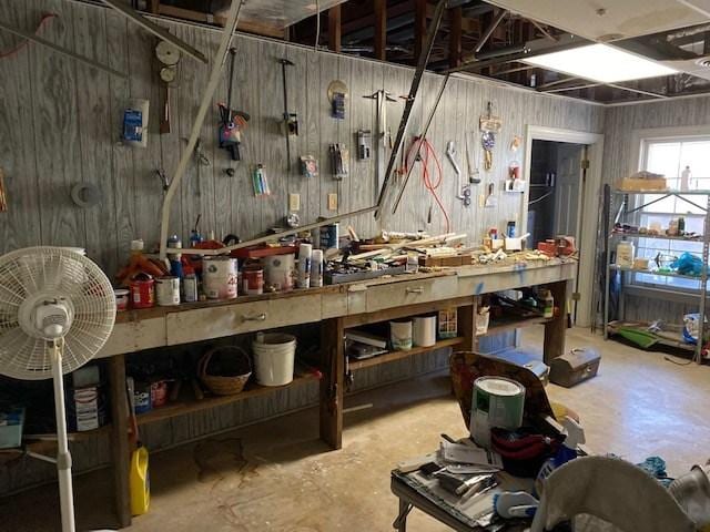 miscellaneous room with wood walls, a workshop area, and concrete floors