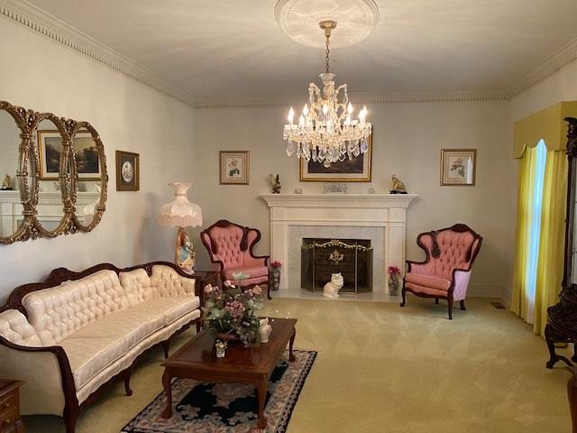 living room with carpet floors, a notable chandelier, and ornamental molding