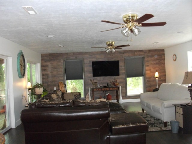 living room with ceiling fan, a fireplace, wood walls, a textured ceiling, and dark hardwood / wood-style flooring