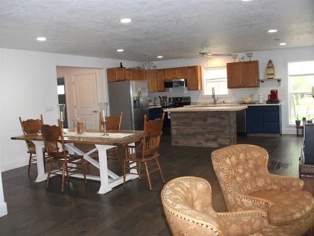 dining area featuring ceiling fan, dark wood-type flooring, sink, and a wealth of natural light