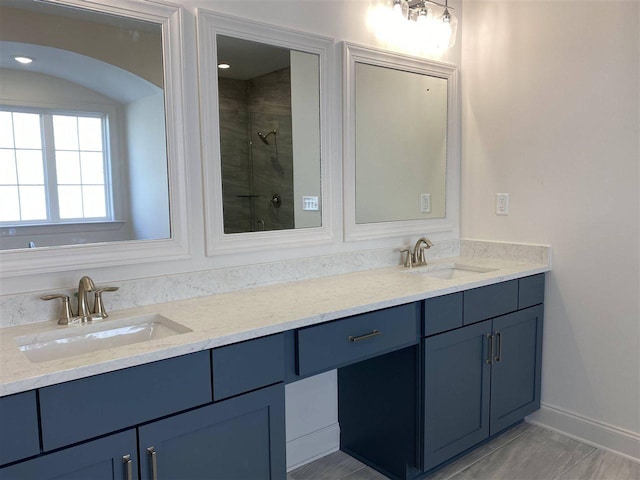 bathroom featuring vanity with extensive cabinet space, dual sinks, and a tile shower