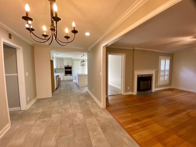 interior space with light hardwood / wood-style floors, ornamental molding, and a notable chandelier