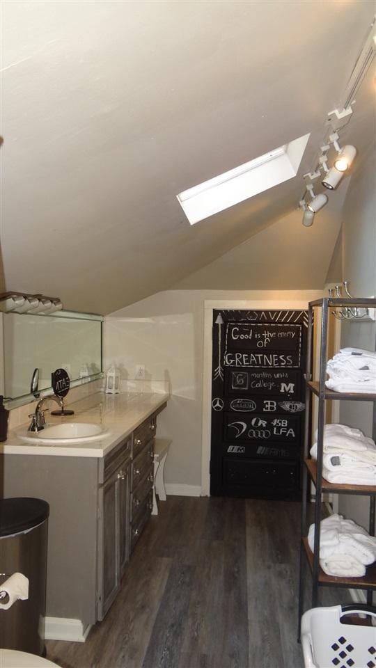 bathroom featuring vanity, hardwood / wood-style flooring, and lofted ceiling with skylight