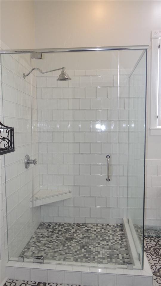 bathroom with a shower with shower door and tile flooring