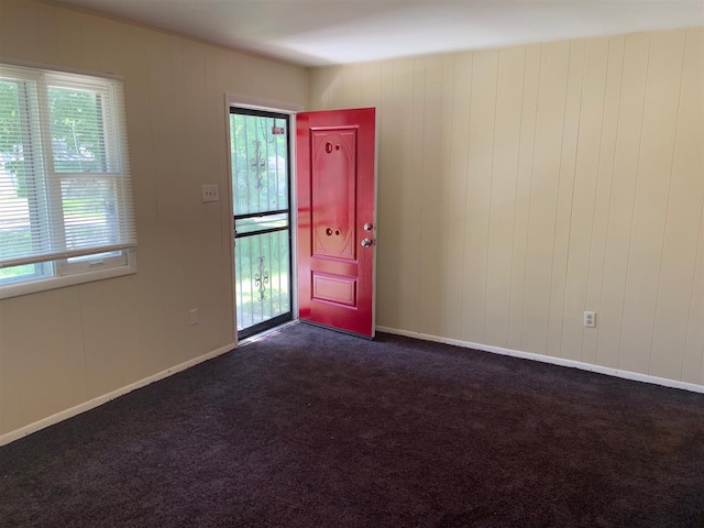 foyer entrance with dark carpet and a wealth of natural light