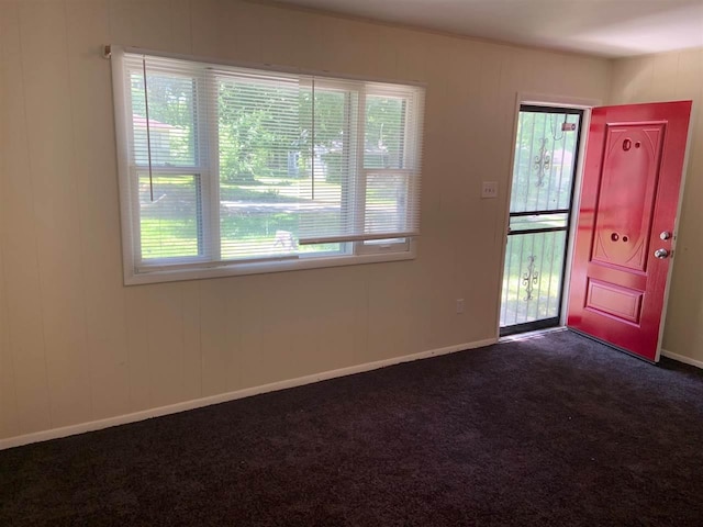 entryway featuring dark carpet and a healthy amount of sunlight