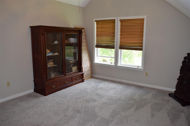 carpeted empty room with vaulted ceiling