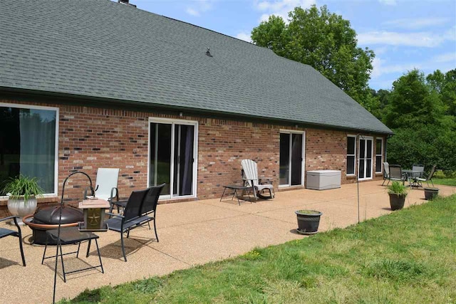 rear view of house with a fire pit, a lawn, and a patio area