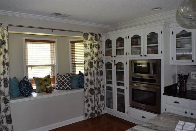 kitchen with white cabinets, a textured ceiling, appliances with stainless steel finishes, and crown molding