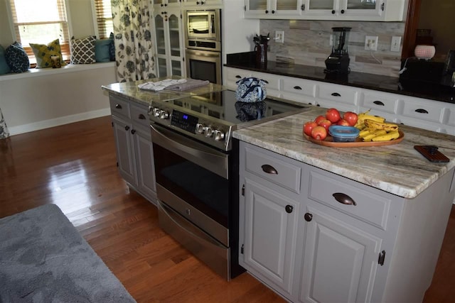 kitchen featuring white cabinets, appliances with stainless steel finishes, tasteful backsplash, and hardwood / wood-style floors