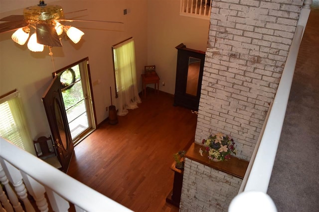 entrance foyer featuring brick wall, dark wood-type flooring, and ceiling fan