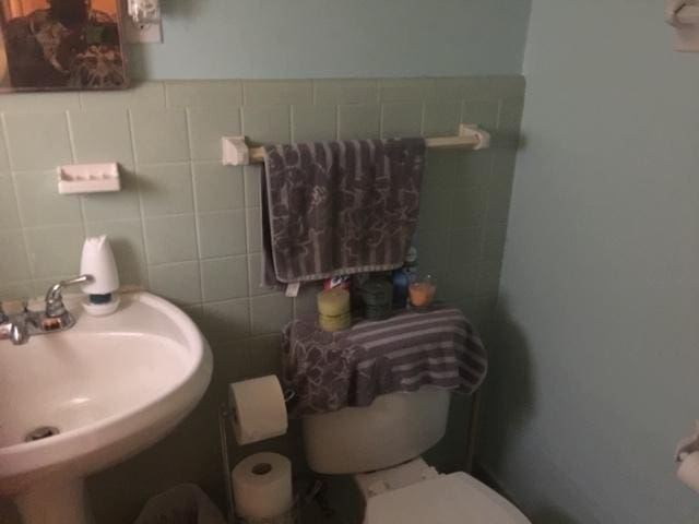 bathroom featuring sink, backsplash, toilet, and tile walls