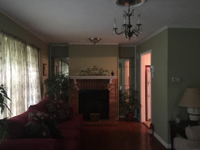 living room featuring a fireplace, ornamental molding, a wealth of natural light, and a chandelier