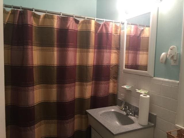 bathroom with backsplash, oversized vanity, and tile walls