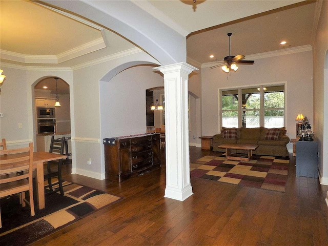 interior space featuring ceiling fan, crown molding, dark wood-type flooring, and decorative columns