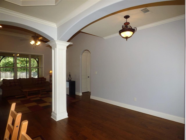 spare room featuring ceiling fan, crown molding, dark wood-type flooring, and ornate columns