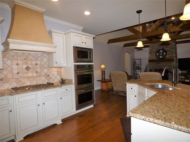 kitchen featuring tasteful backsplash, custom range hood, stainless steel appliances, ceiling fan, and sink