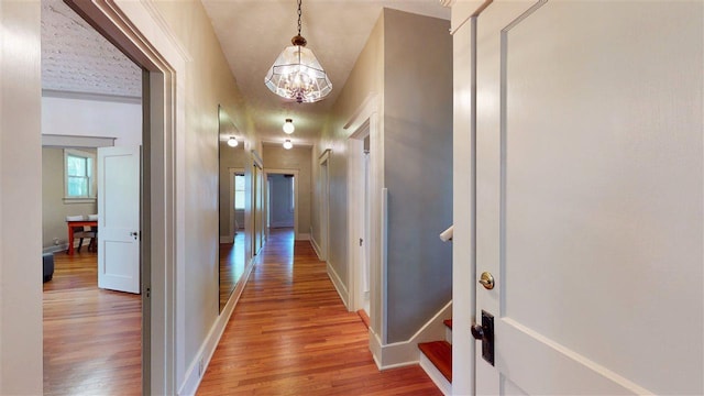 hallway with a notable chandelier and light hardwood / wood-style floors