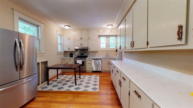 kitchen with sink, light hardwood / wood-style flooring, appliances with stainless steel finishes, and white cabinetry