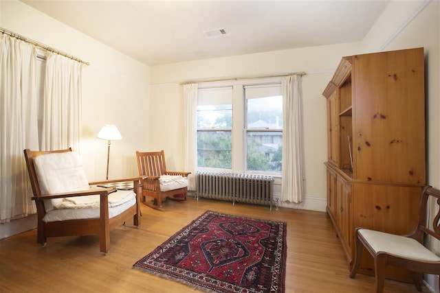 sitting room featuring radiator heating unit and light wood-type flooring