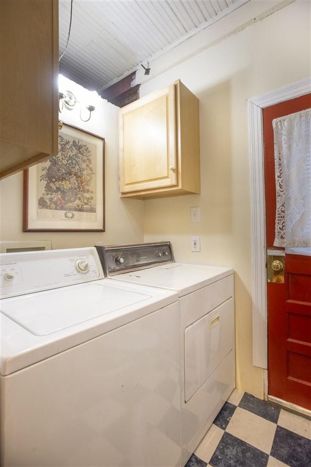 clothes washing area featuring washer and clothes dryer, cabinets, and light tile floors