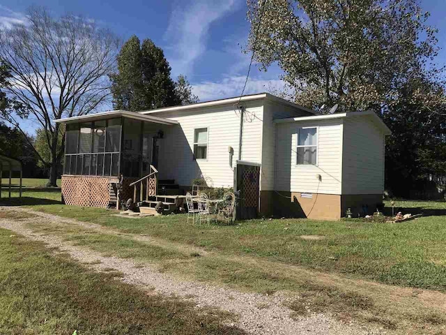 rear view of property featuring a sunroom and a yard