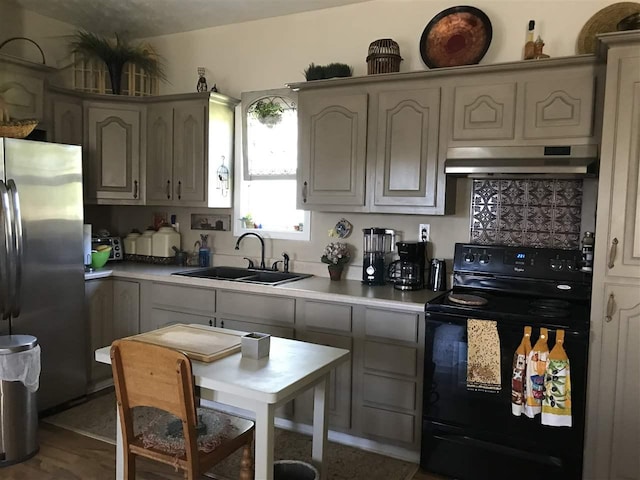 kitchen with electric range, sink, wall chimney range hood, gray cabinets, and stainless steel refrigerator