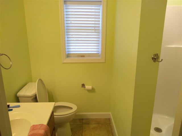 bathroom with tile floors, toilet, vanity, and a healthy amount of sunlight