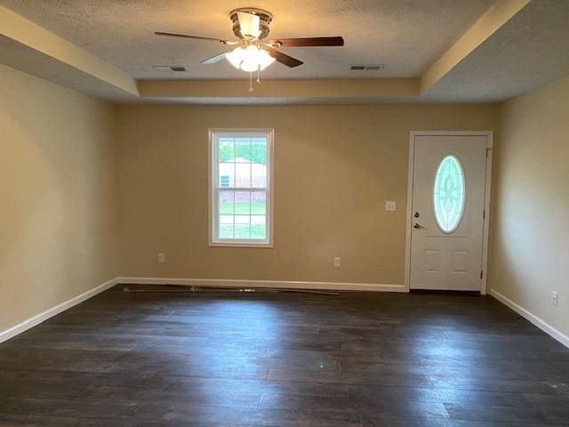 entryway with dark wood-type flooring, a textured ceiling, a tray ceiling, and ceiling fan