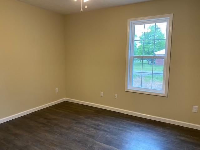 unfurnished room with ceiling fan and dark wood-type flooring