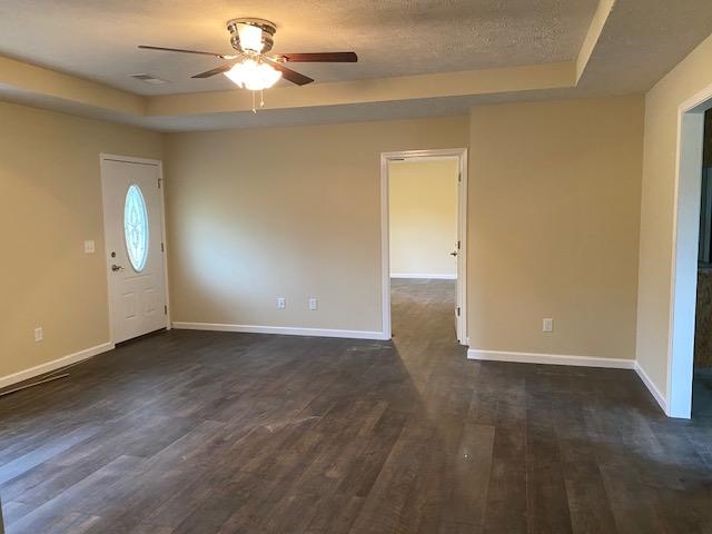 spare room featuring dark hardwood / wood-style flooring, ceiling fan, and a tray ceiling