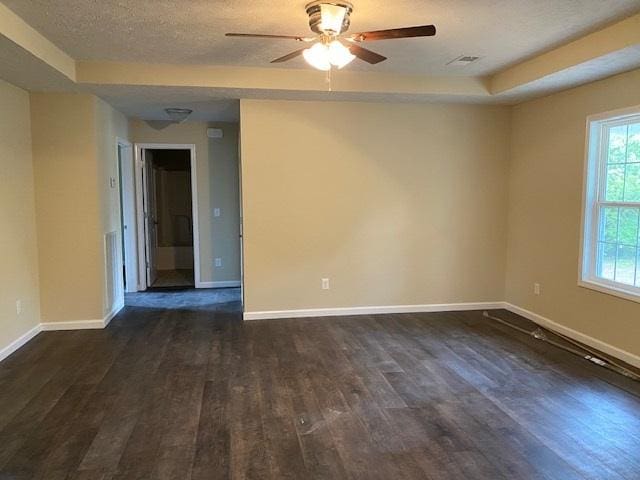 spare room featuring ceiling fan, dark hardwood / wood-style floors, a tray ceiling, and a textured ceiling