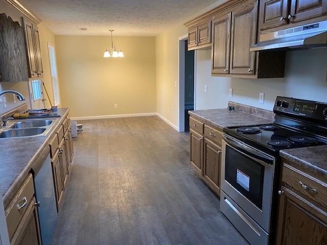 kitchen with dark wood-type flooring, electric stove, sink, a notable chandelier, and hanging light fixtures