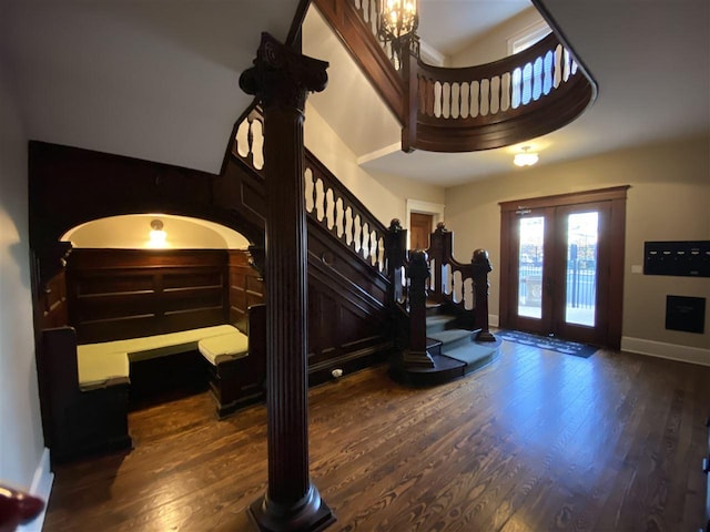 foyer featuring a chandelier, a towering ceiling, dark wood-type flooring, and french doors