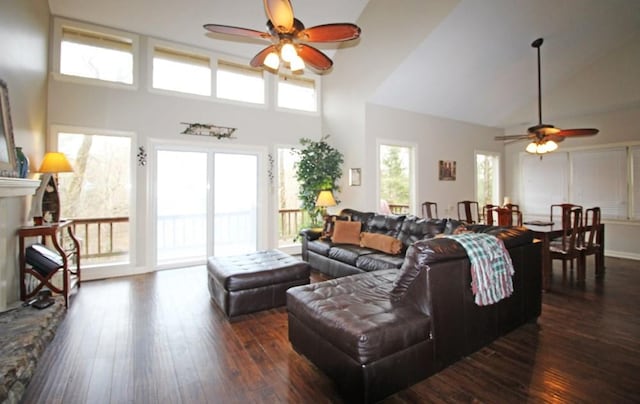 living room with ceiling fan, dark wood-type flooring, and a towering ceiling