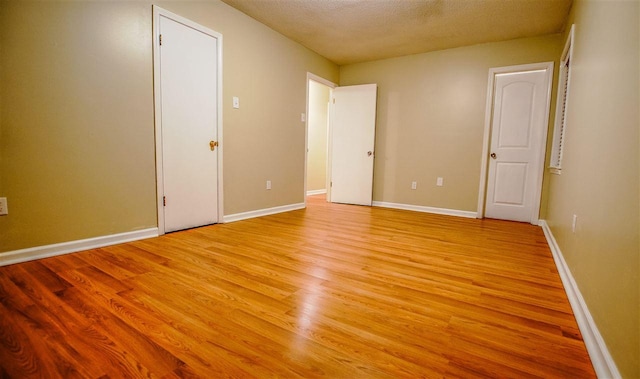 unfurnished room featuring a textured ceiling and light hardwood / wood-style floors