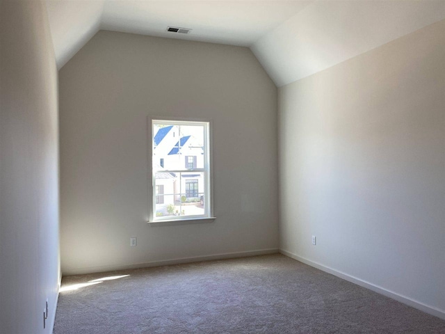 carpeted empty room with vaulted ceiling