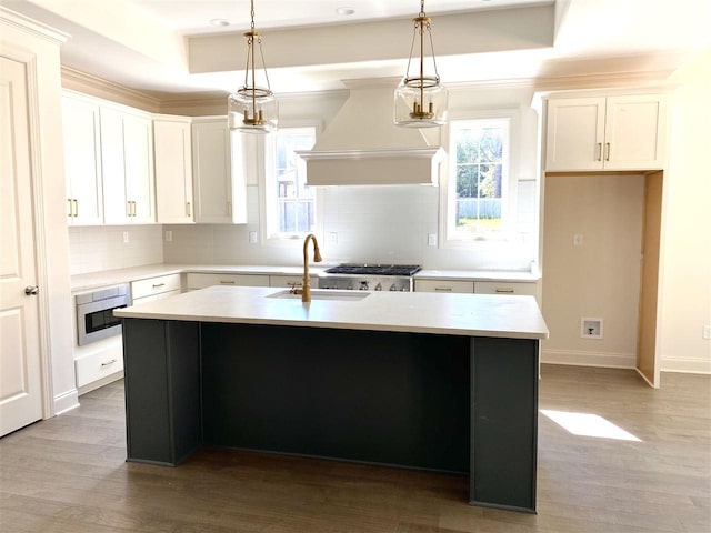 kitchen with hardwood / wood-style floors, a center island with sink, custom range hood, and white cabinetry