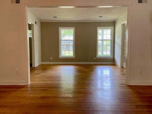 unfurnished room featuring ornamental molding, a textured ceiling, a wealth of natural light, and light wood-type flooring